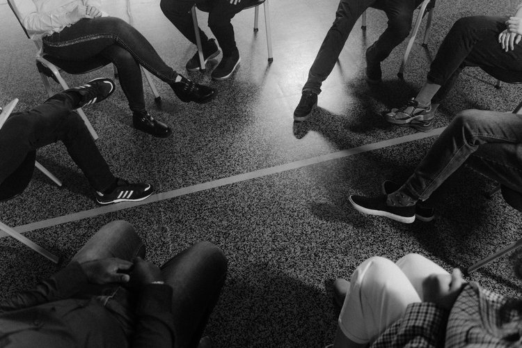 Junge Menschen sitzen im Kreis (Bild in Schwarz-weiß).