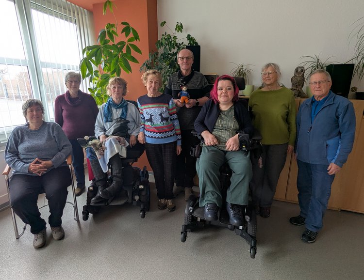 Acht Mitglieder der Selbsthilfegruppe stehen und sitzen nebeneinander