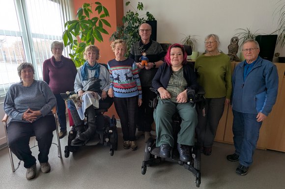 Acht Mitglieder der Selbsthilfegruppe stehen und sitzen nebeneinander