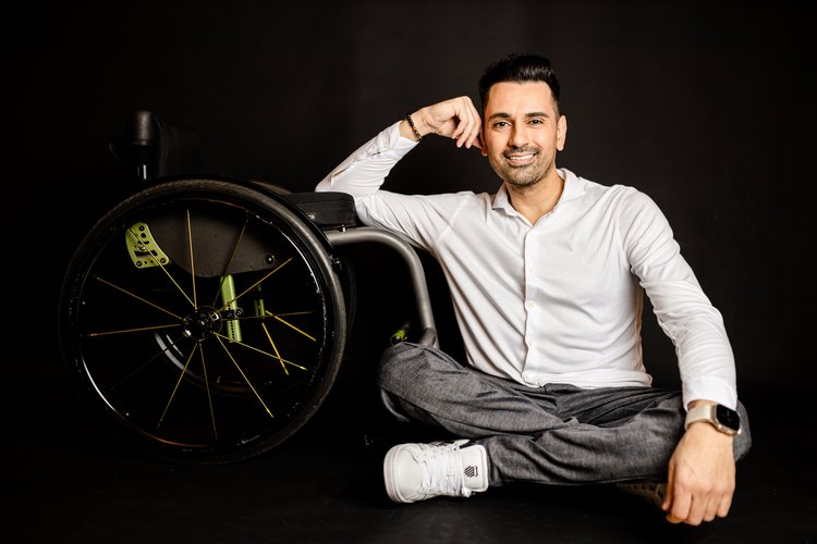 Comedian und Schauspieler Tan Caglar sitzt neben seinem Rollstuhl