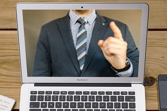 Foto: Laptop mit Mann im Anzug und gestrecktem Zeigefinger nach oben (Quelle: pixabay.com)